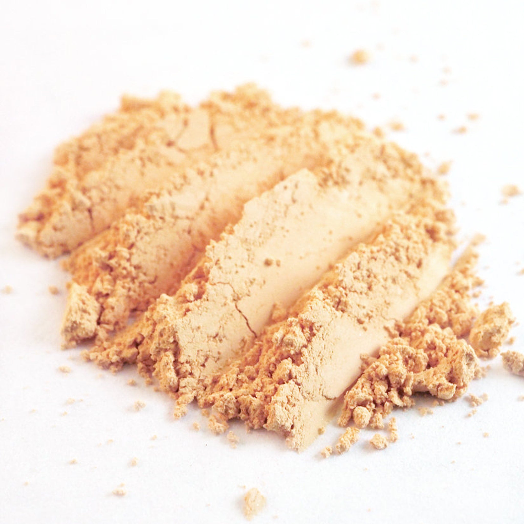 Close-up of matte pastel peach loose pigment eyeshadow in apricot ivory, showing fine powder texture