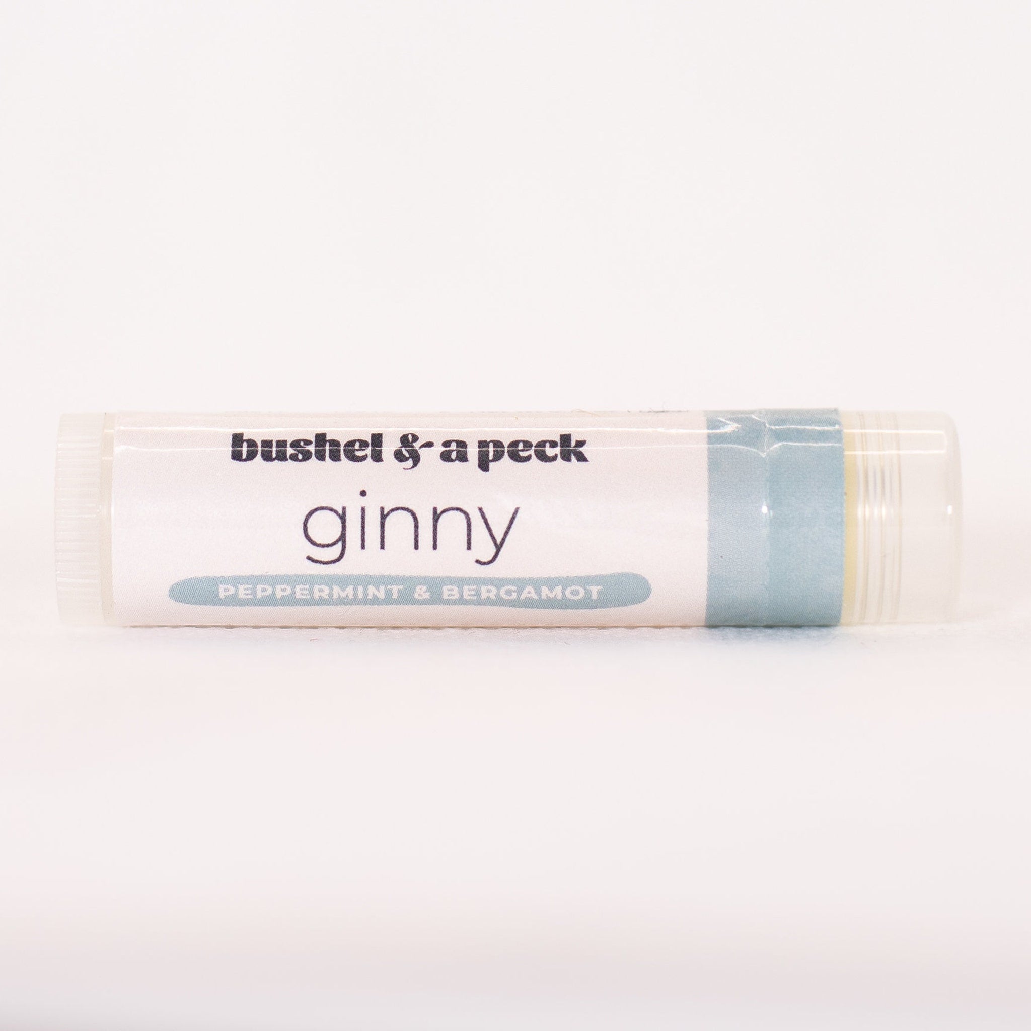 Lip balm tube with white label, light blue accent, and "Bushel & a Peck" text