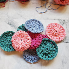 Crochet washcloths in various colors, round shape, handmade cotton texture, scattered on surface