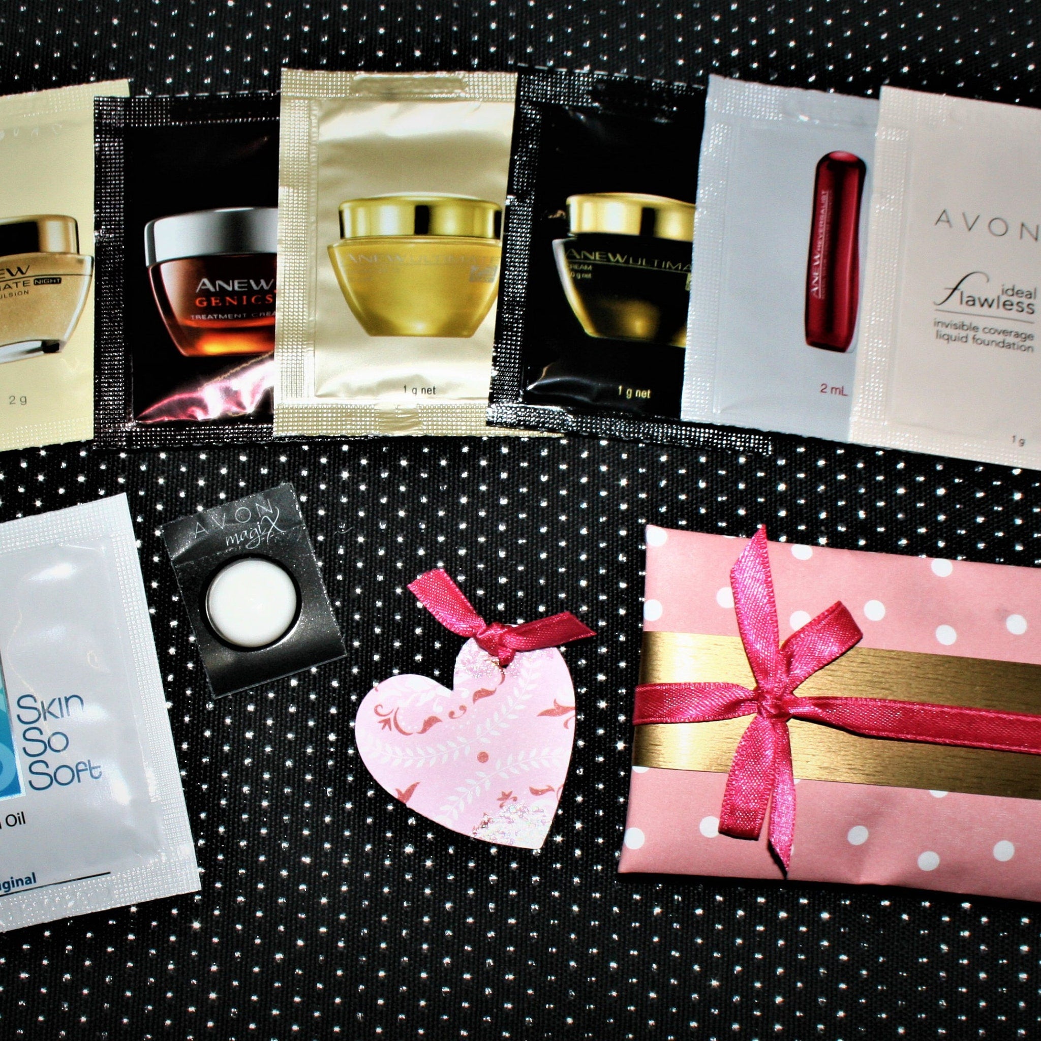 Skincare samples with black, white, and gold packaging, plus pink heart and gift wrap with ribbon