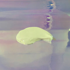 Cream swatch, light green color, smooth texture, on iridescent background