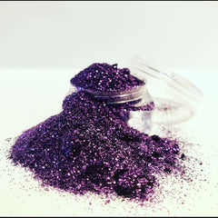 Hand applying shimmering silver loose glitter eyeshadow to eyelid with a small brush
