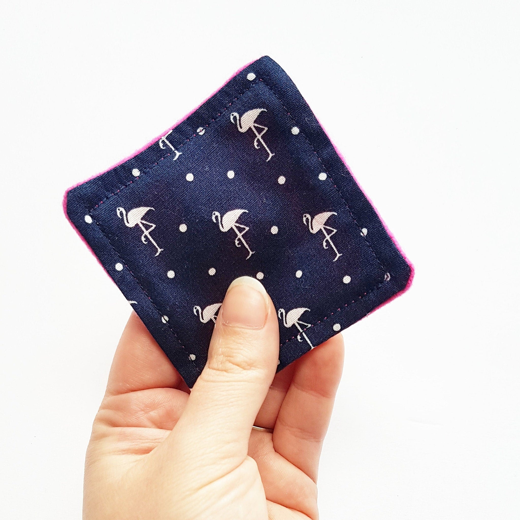 Navy square fabric with flamingo pattern and pink trim, held in hand