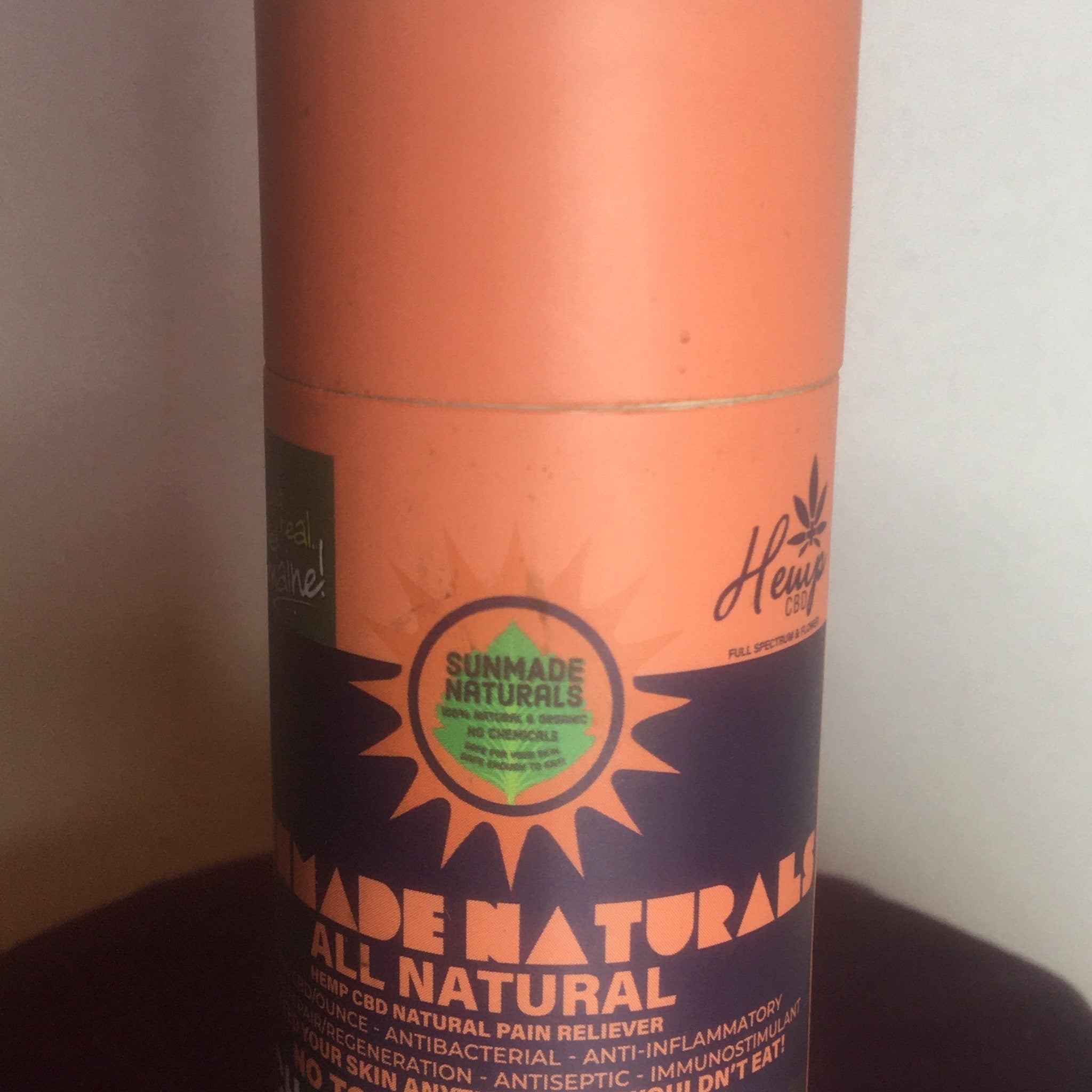 Hemp CBD product, orange and purple cylindrical container, Sunmade Naturals brand label visible