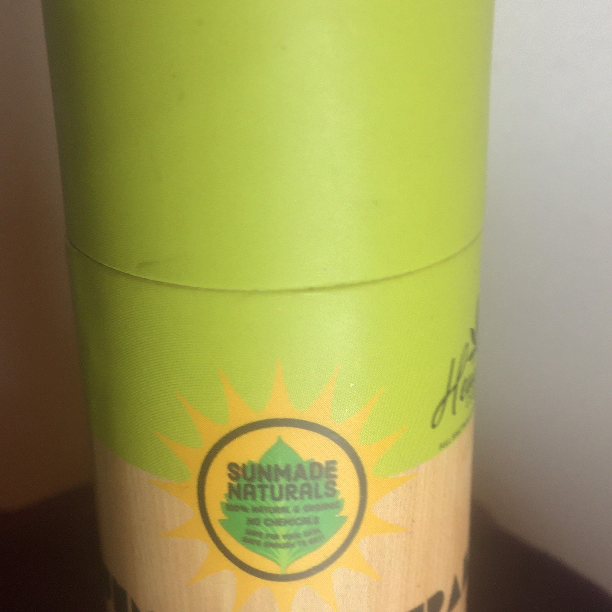 Sunmade Naturals packaging with green, yellow, and brown colors, cylindrical shape, and brand logo visible