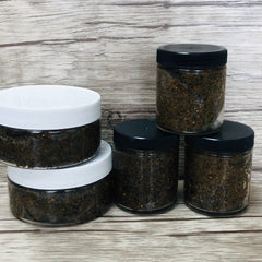 Jarred scrub with black and white lids, clear glass jars, and brown scrub contents.