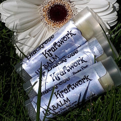Lip balm tubes with Blackrose Kraftwork text, blue and silver labels, displayed in grass