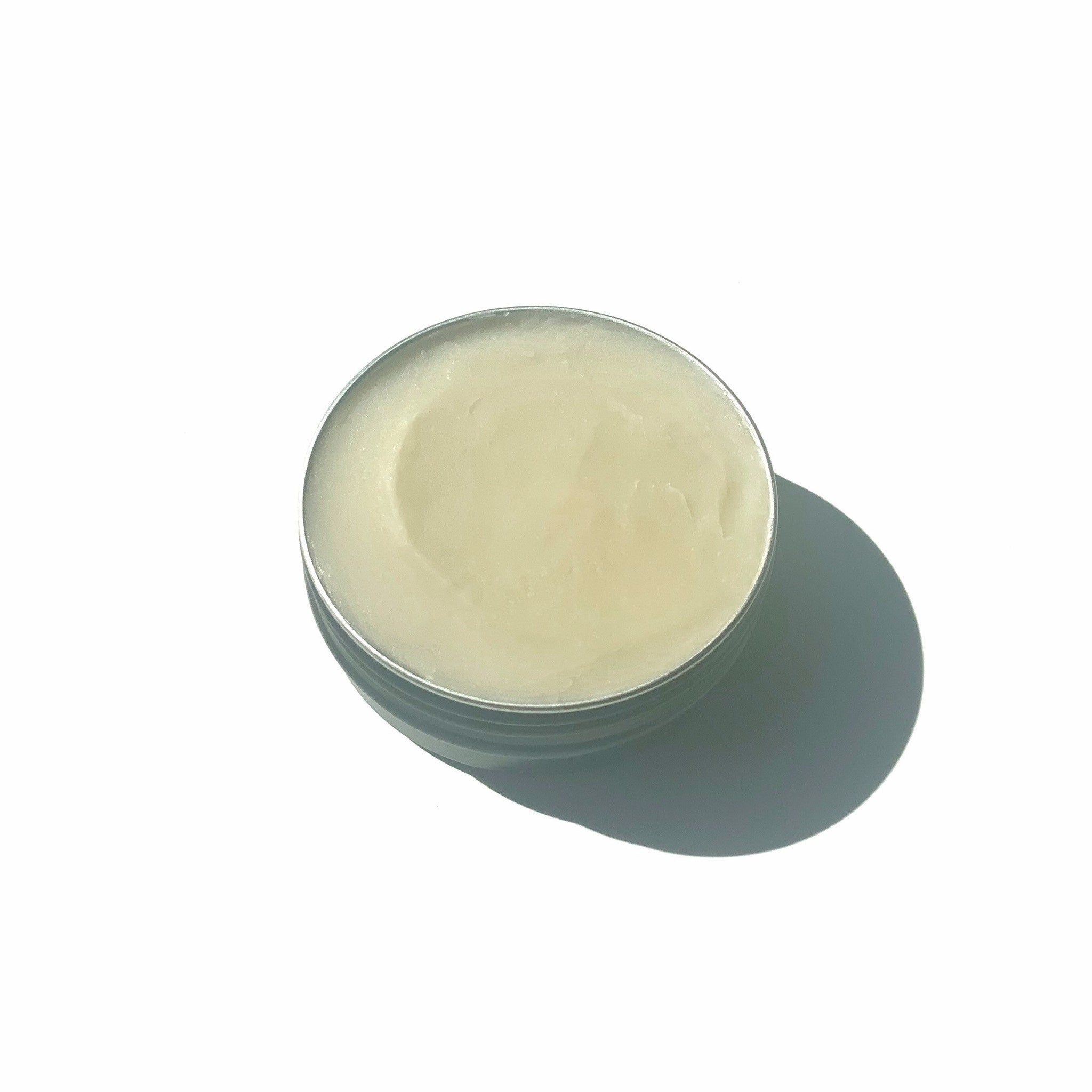 Balm in a metal tin, light yellow color, smooth texture, round shape