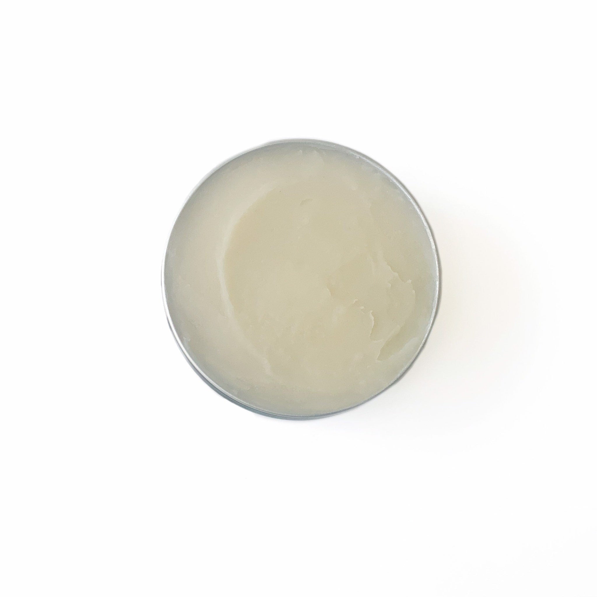 Cream balm in a silver metal tin, light beige color, smooth texture, overhead view