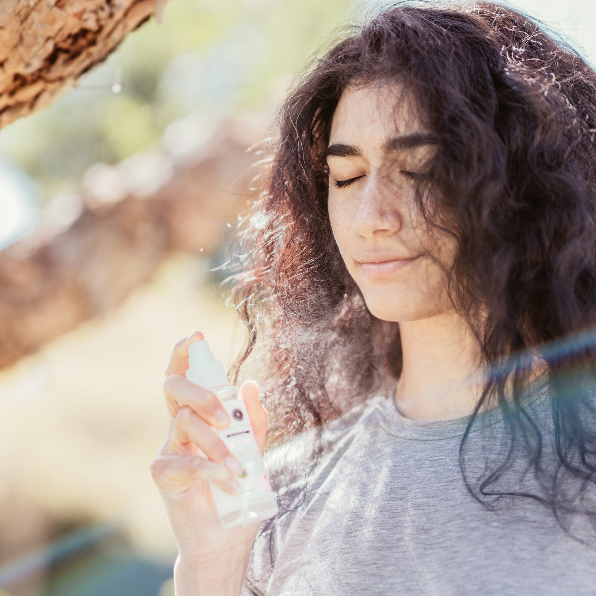 Spray bottle with white bottle, clear liquid, woman spraying hair
