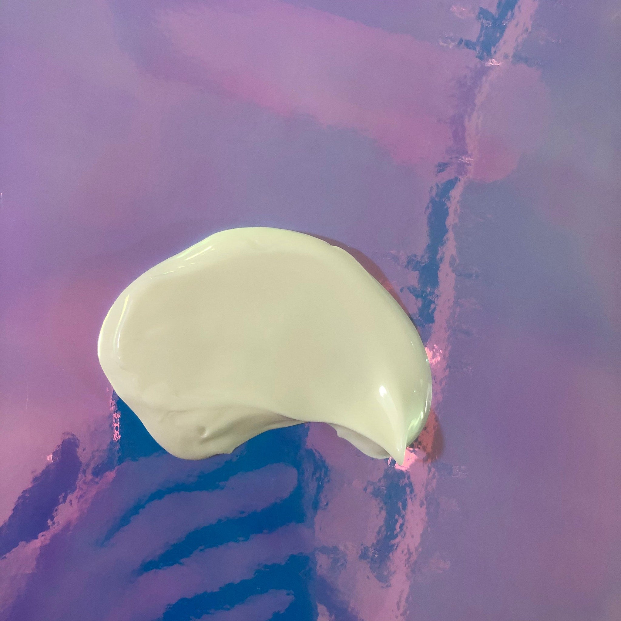 White cream swatch on iridescent purple and blue background