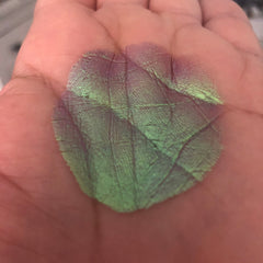 Eye shadow swatch with green and purple multichrome color, textured pattern, on hand