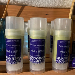 Heel balm sticks with white lids, green balm, and Wise Lyon Soapworks label with floral design