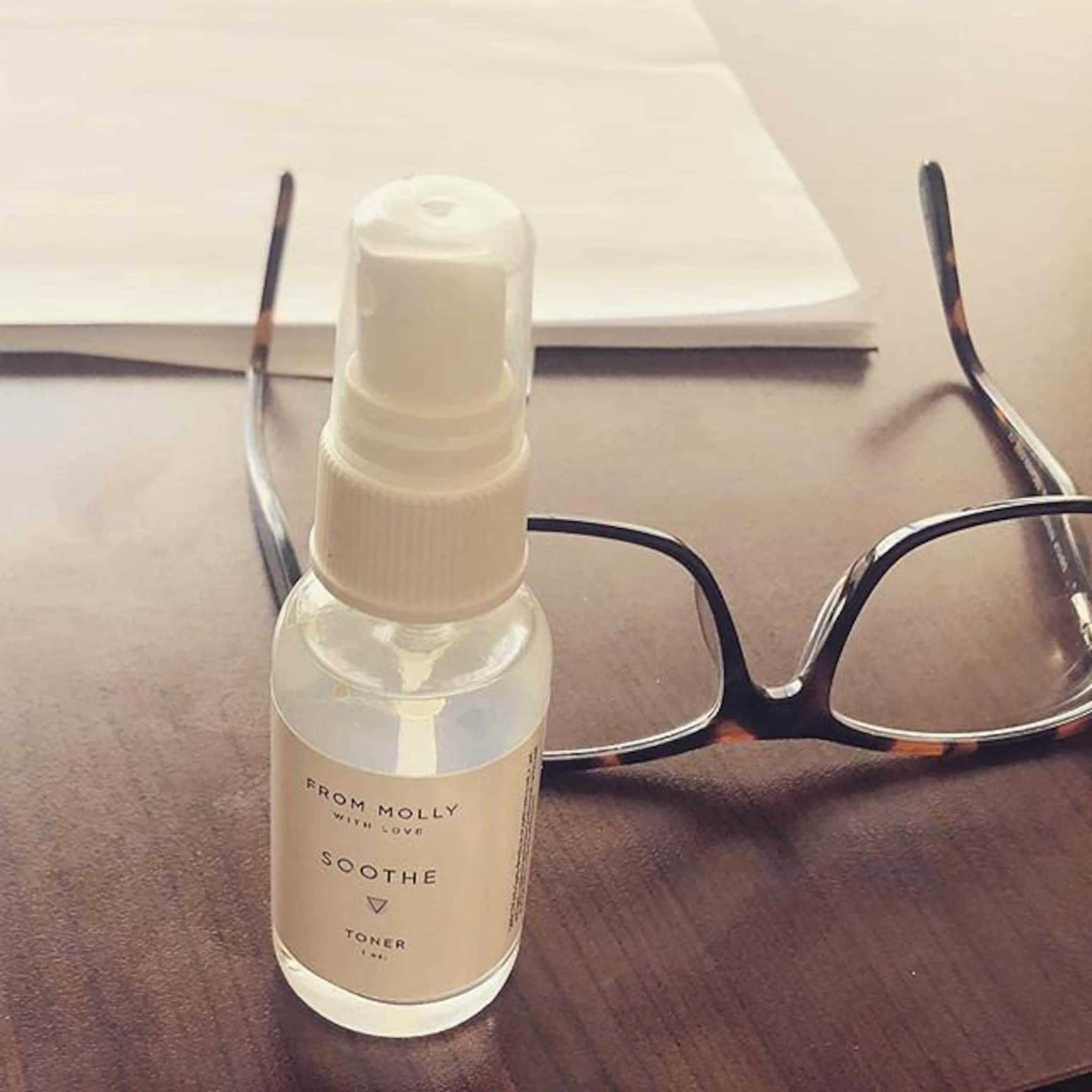 Toner bottle with white cap and label, clear liquid, and tortoiseshell glasses on table