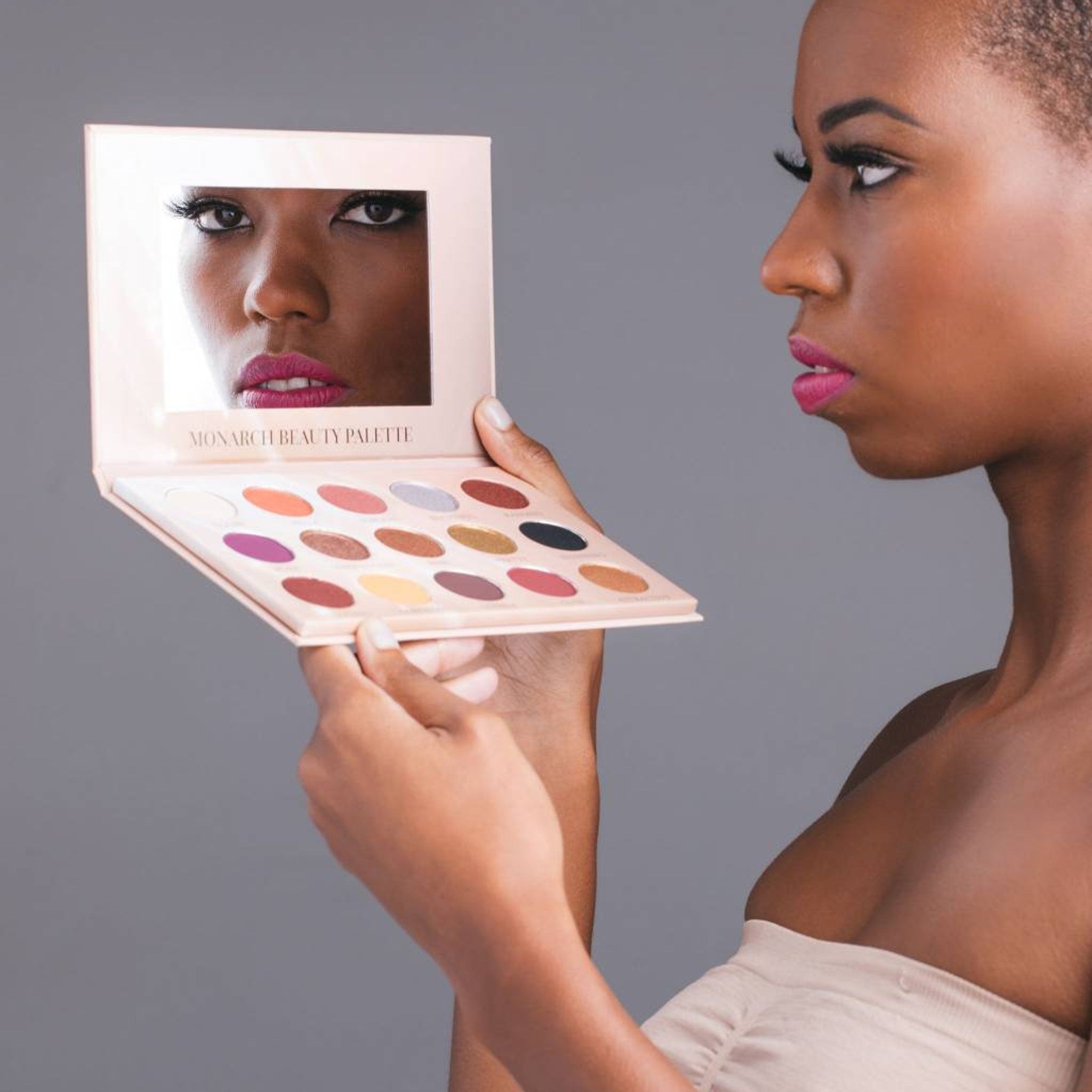 Close-up of Monarch & Queen Alexandra eyeshadow duo showing shimmering gold and deep plum shades with embossed patterns