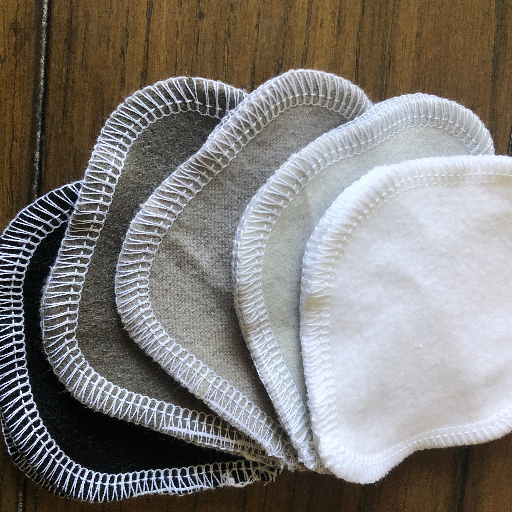 Reusable facial rounds in various colors with white stitched edges and soft material