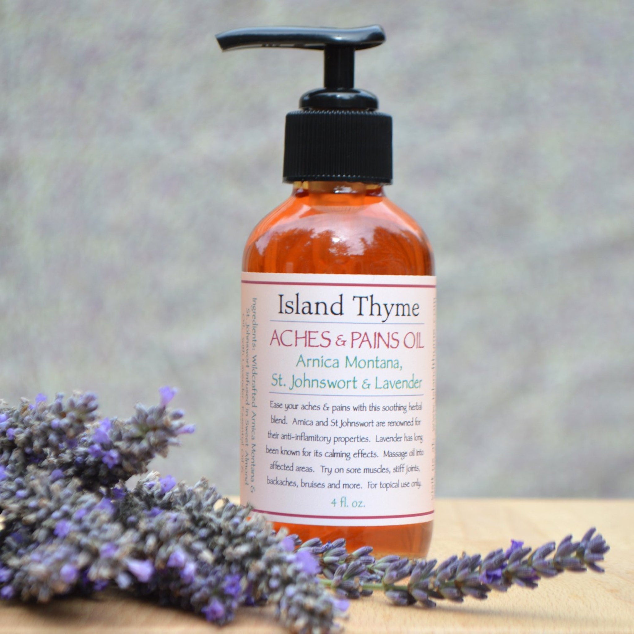 Aches and pains oil bottle with black pump, amber liquid, and Island Thyme label with lavender sprigs