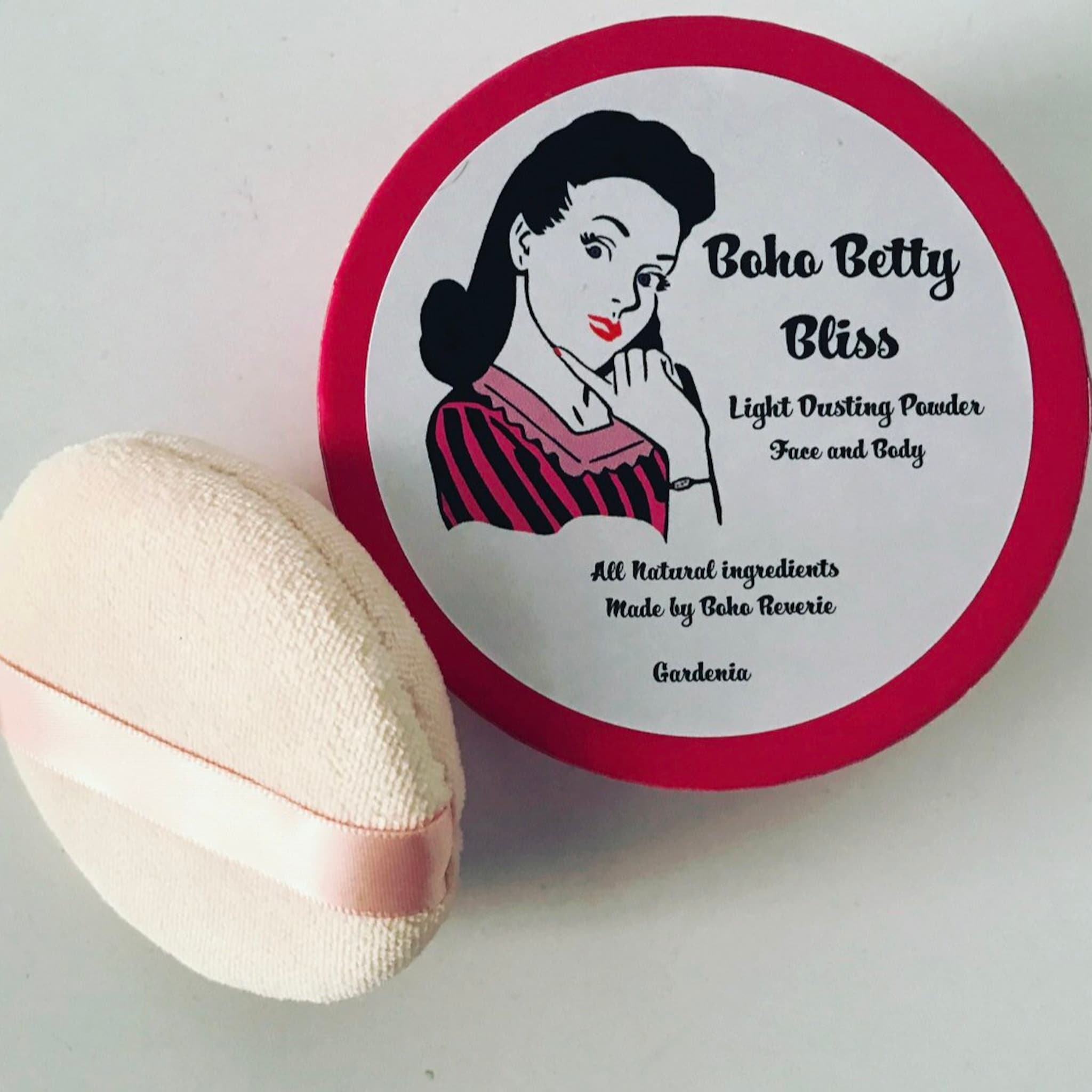 Dusting powder with red rim, pink ribbon, and Boho Betty Bliss label on white background