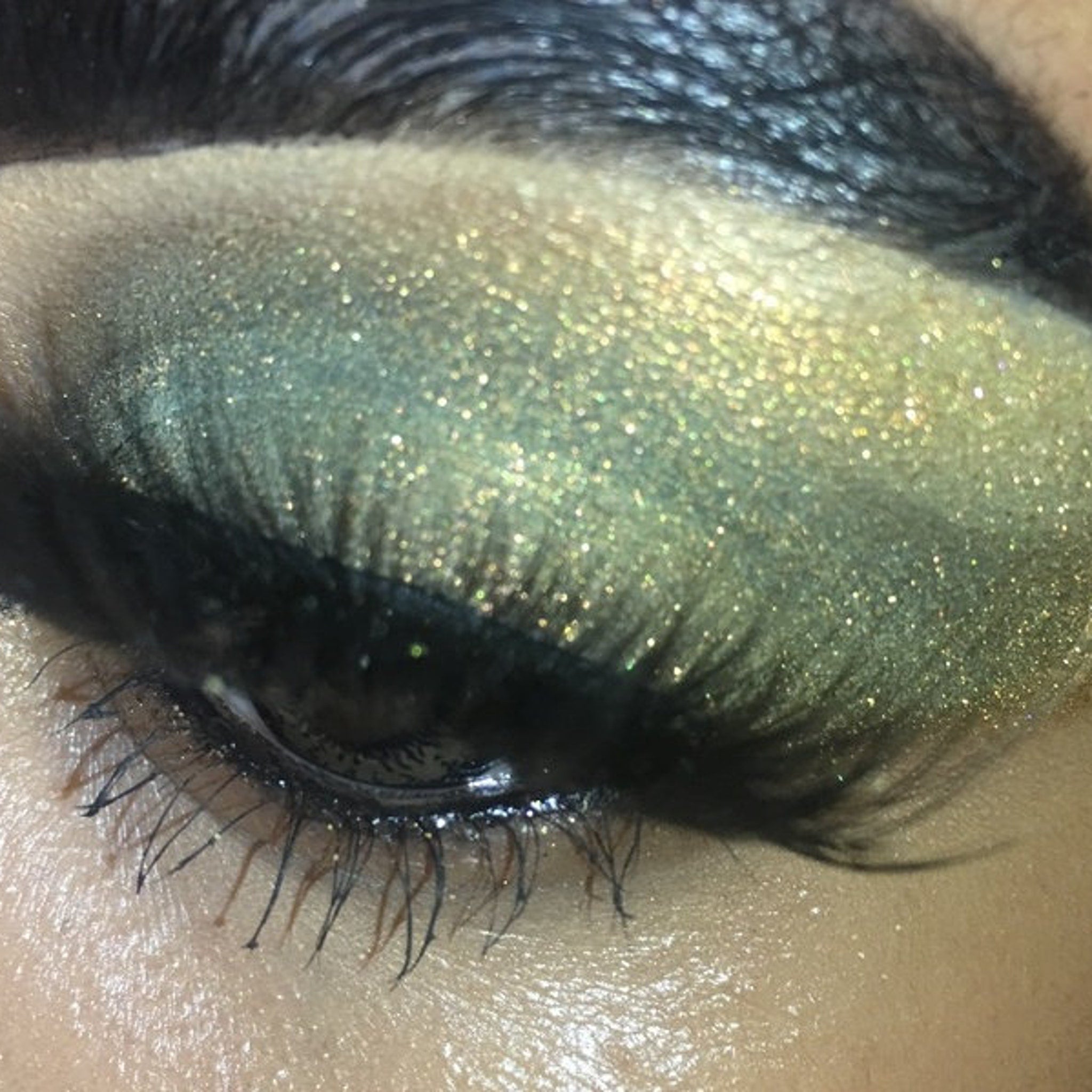 Close-up of amber moss shifter eyeshadow pan showing shimmer particles catching light