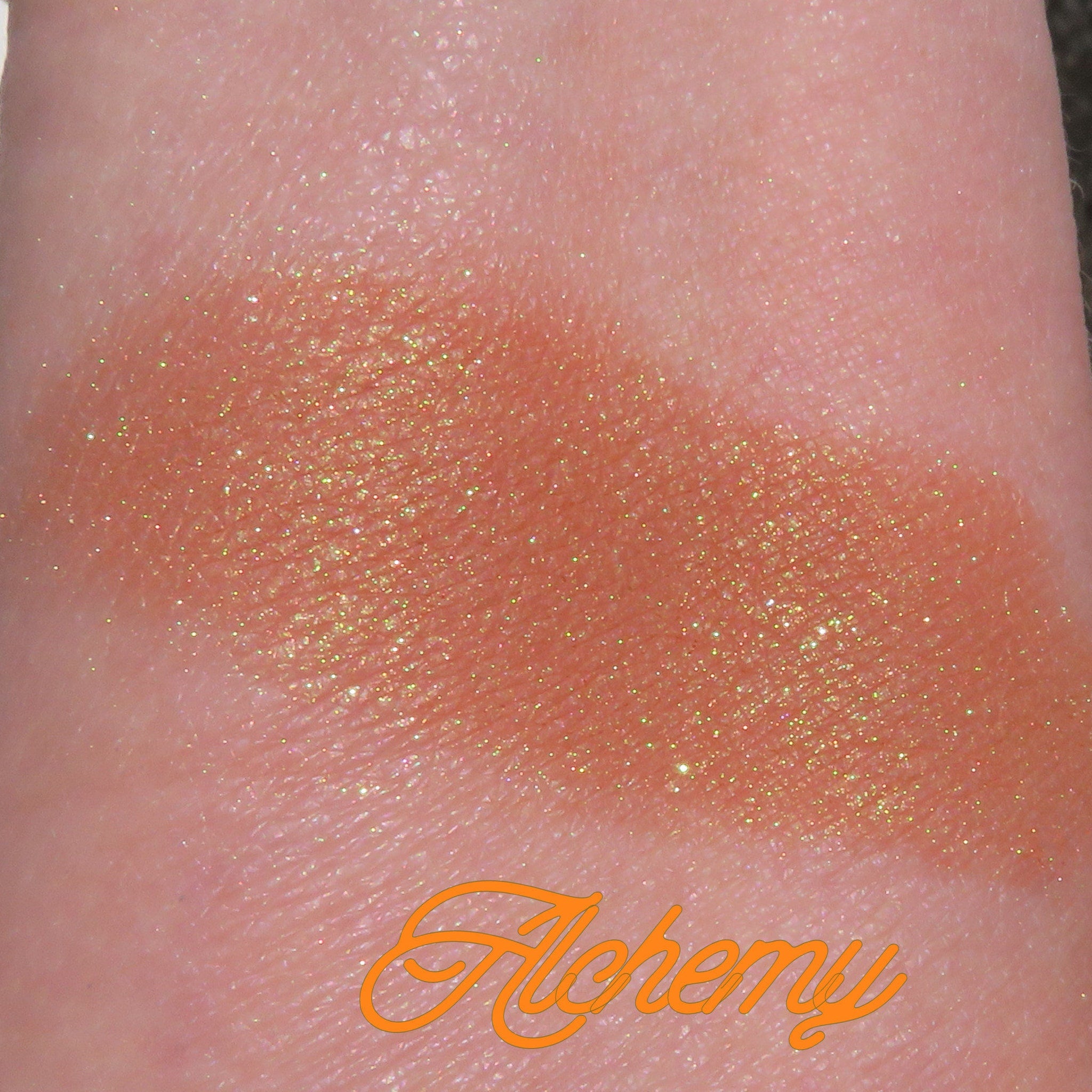 Side view of loose brown gold mineral eyeshadow with golden shimmer in a small jar, showcasing texture and depth