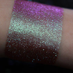 Close-up of fingertips applying shimmery teal and purple mermaid eye shadow to eyelid