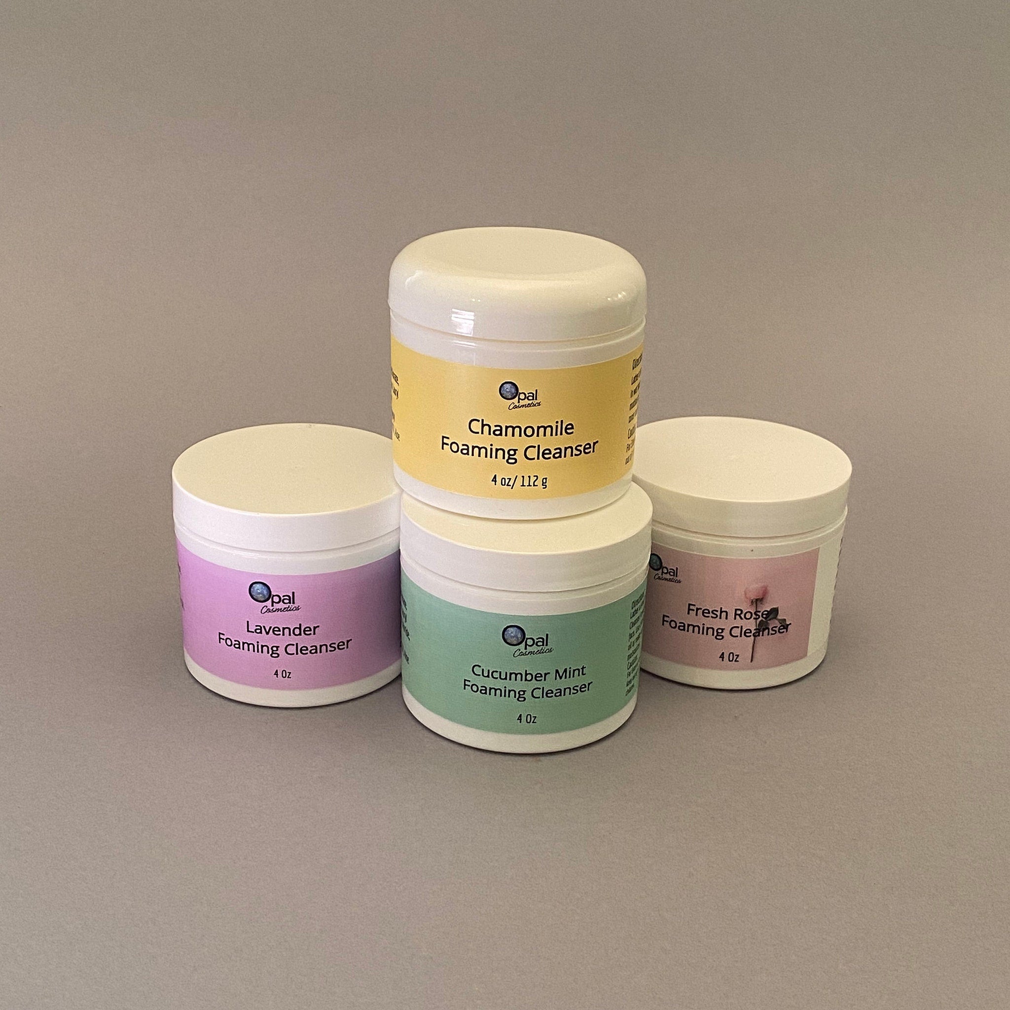 Foaming cleanser jars in white, yellow, pink, and green with Opal Cosmetics branding and labels