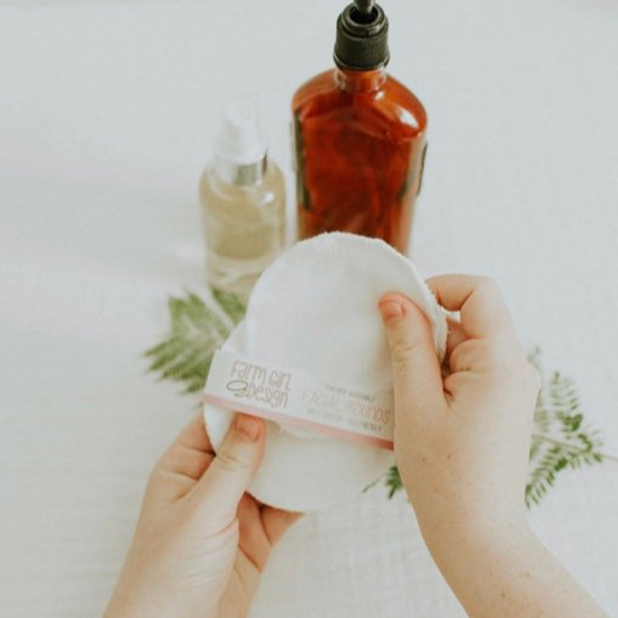 Facial rounds, white cotton, Farm Girl Design, held in hands, with other products in background