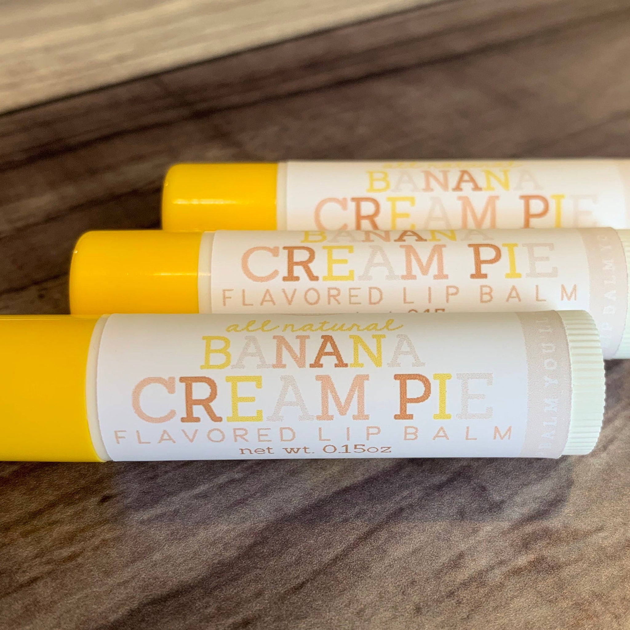 Lip balm tubes with yellow caps and white labels featuring "Banana Cream Pie" text