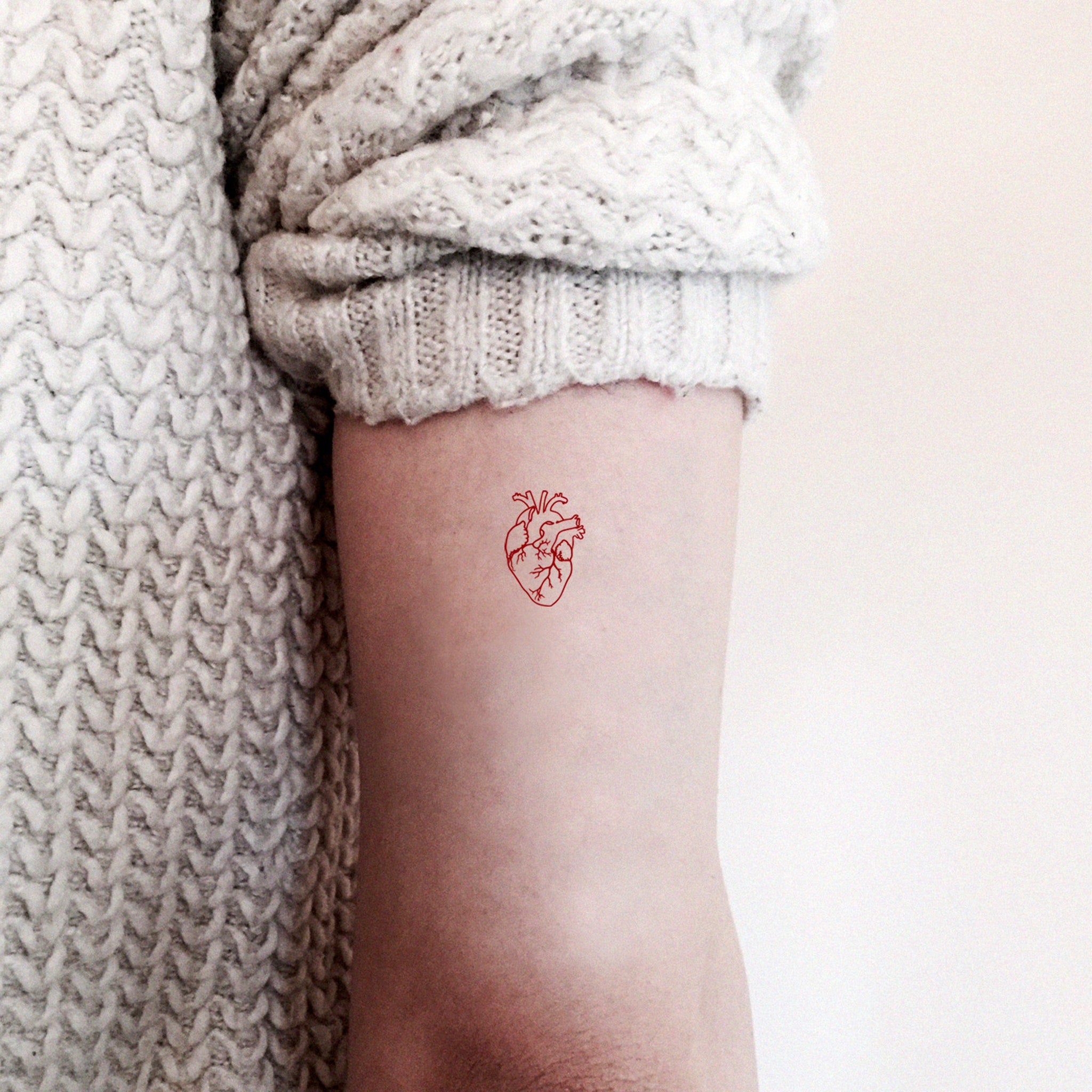 Set of three anatomical heart temporary tattoos with intricate red detailing on clear backing
