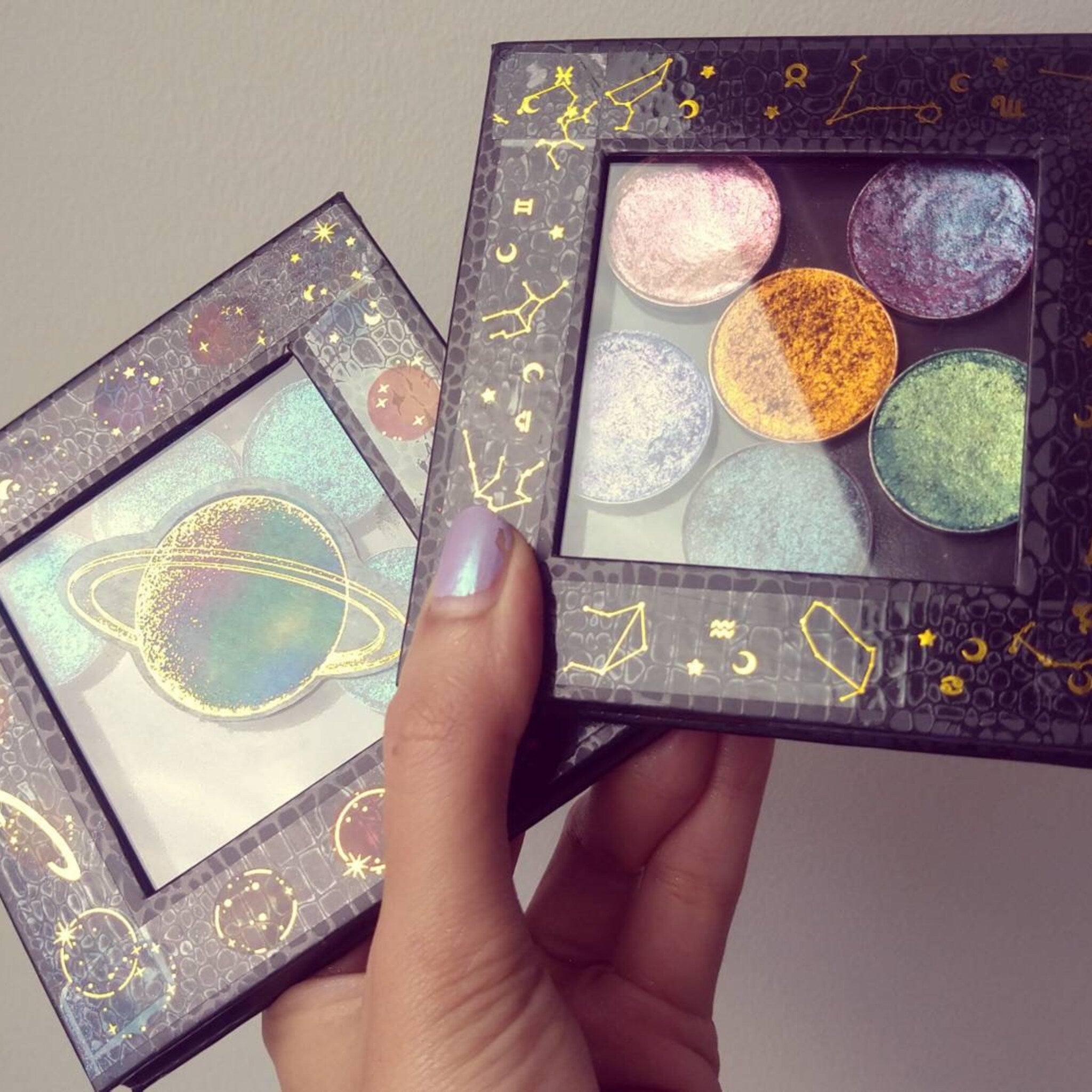 Close-up of multichrome pressed eyeshadow pan showing vibrant color shift from teal to purple under light
