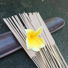 Incense sticks beige color with yellow flower on a wooden tray, natural style