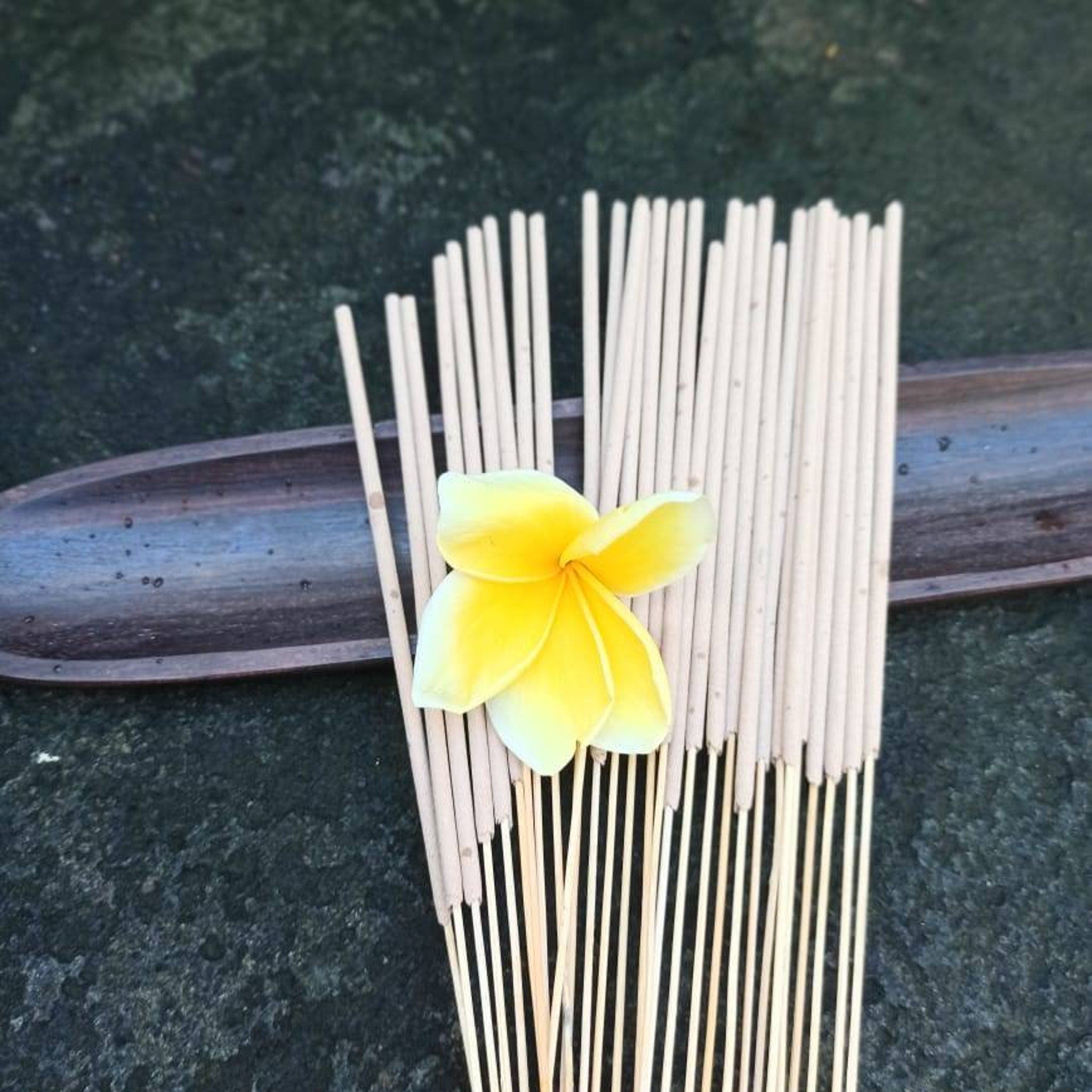 Incense sticks with light brown color, natural wood material, and a yellow flower on top