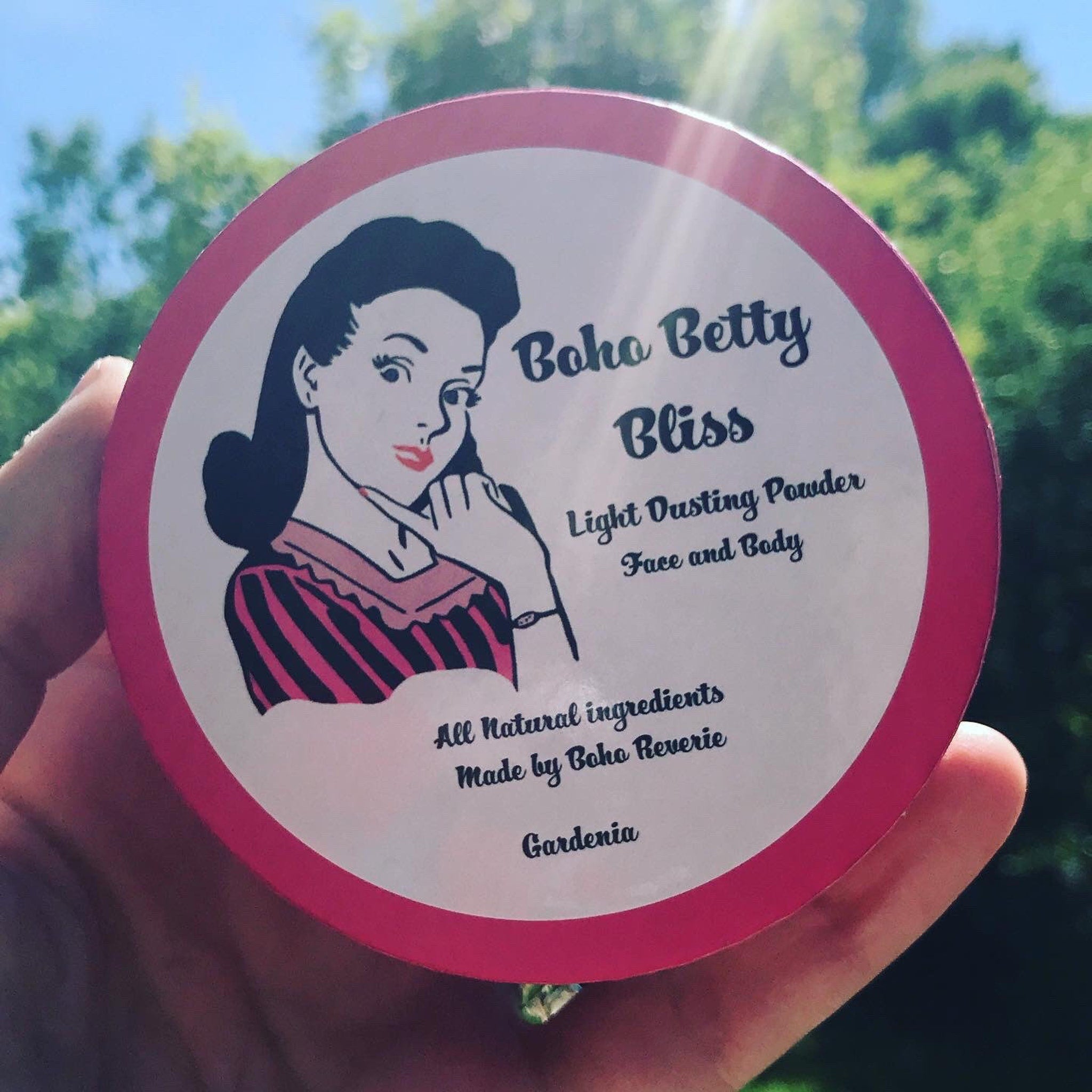 Dusting powder container with pink rim, white center, and Boho Betty Bliss text and illustration