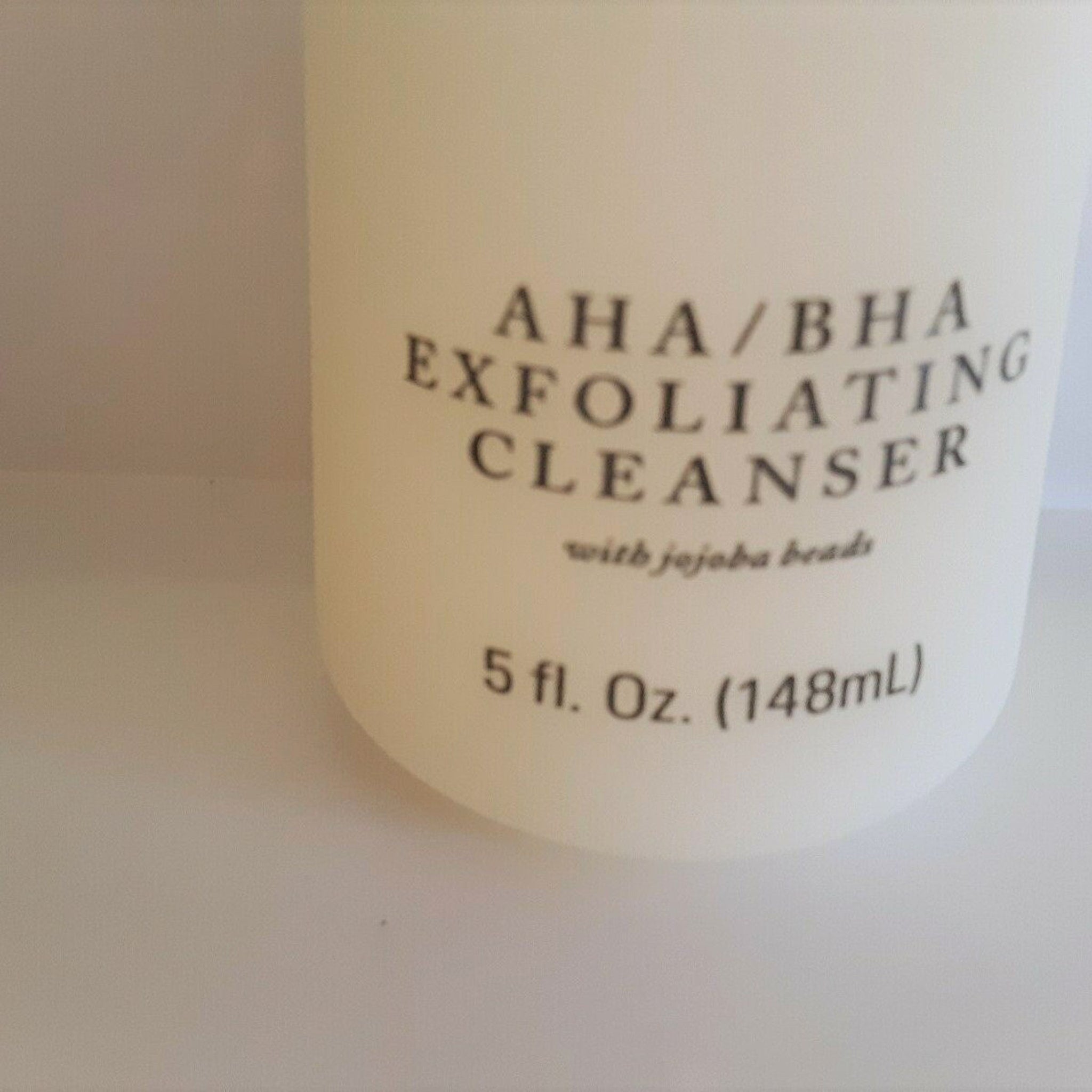 Exfoliating cleanser bottle, white with black text, AHA/BHA formula visible