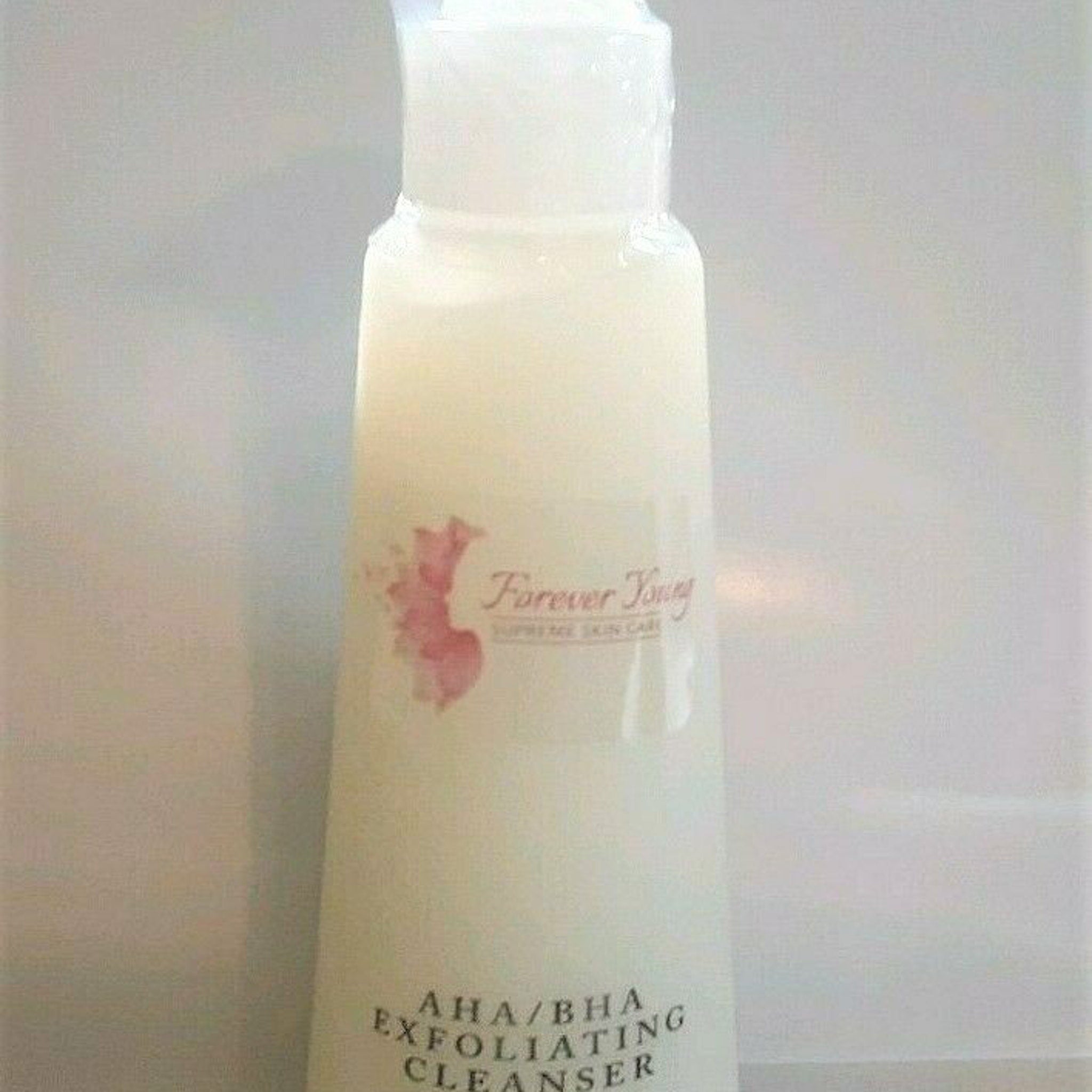 AHA/BHA exfoliating cleanser bottle, white and cream colored, with "Forever Young" text visible