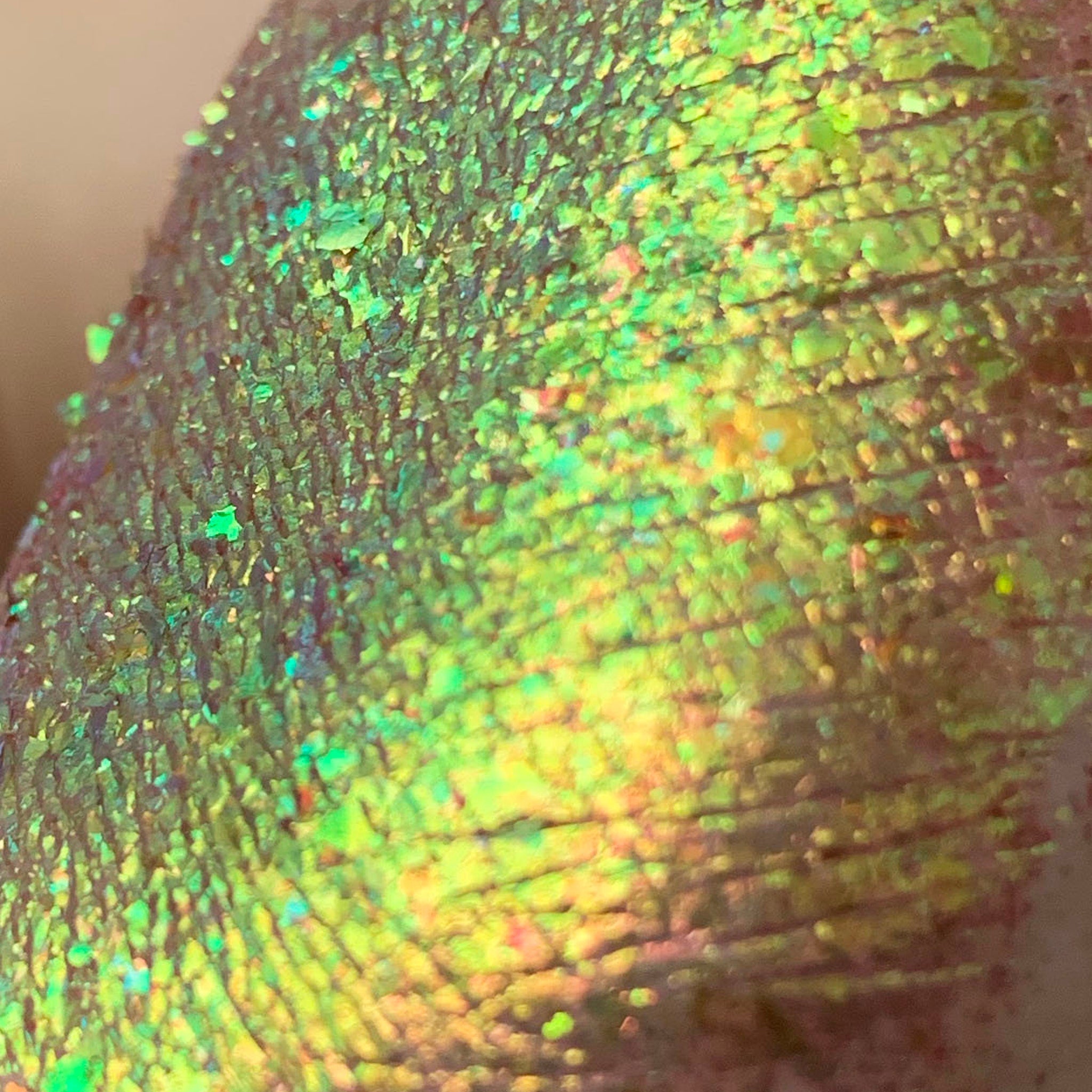 Side view of Tala Foil Lizard Eye Shadow Pigment FL12 showing iridescent green-gold shimmer in angled light