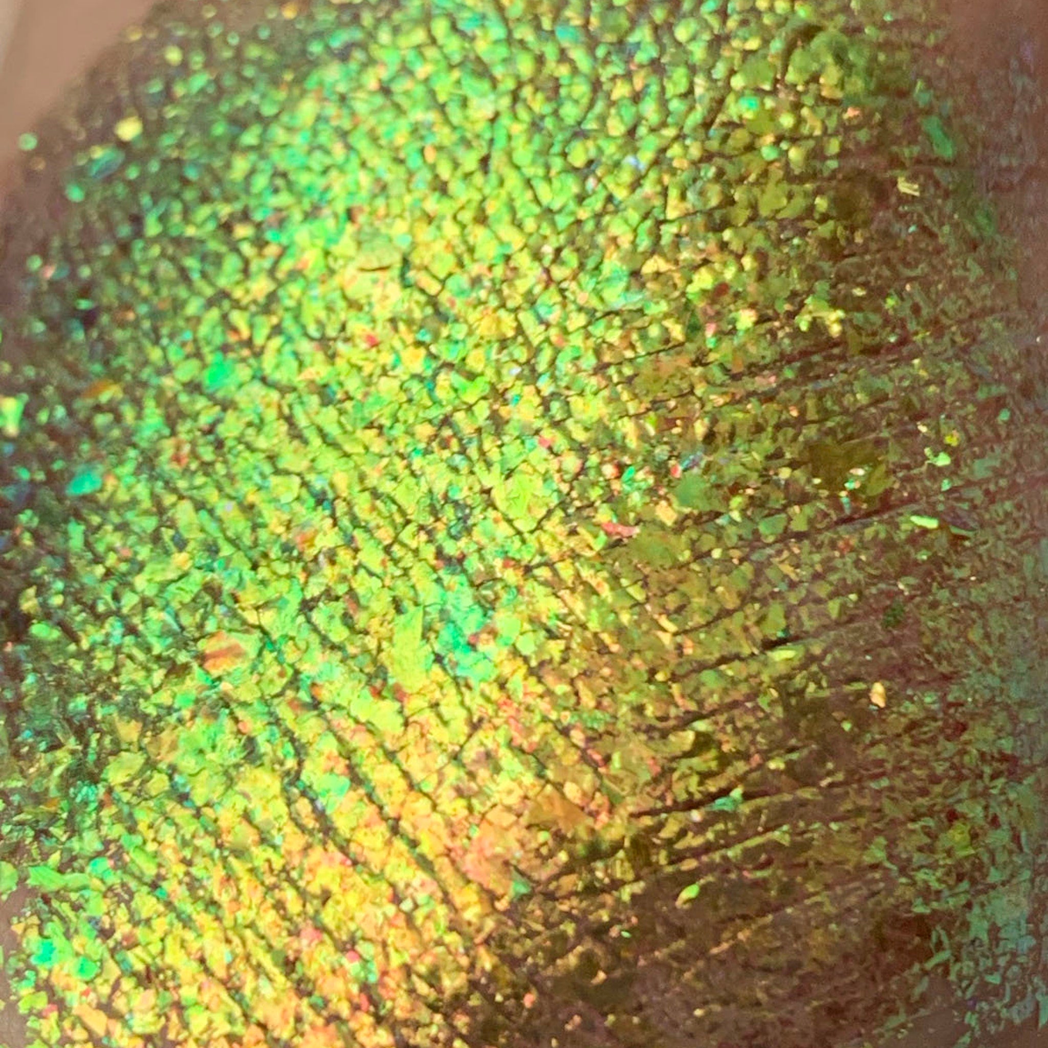 Close-up of Tala Foil Lizard Eye Shadow Pigment FL12 showing iridescent green-gold shimmer texture in compact jar