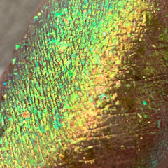 Iridescent green and gold textured surface with cracked pattern and light reflections