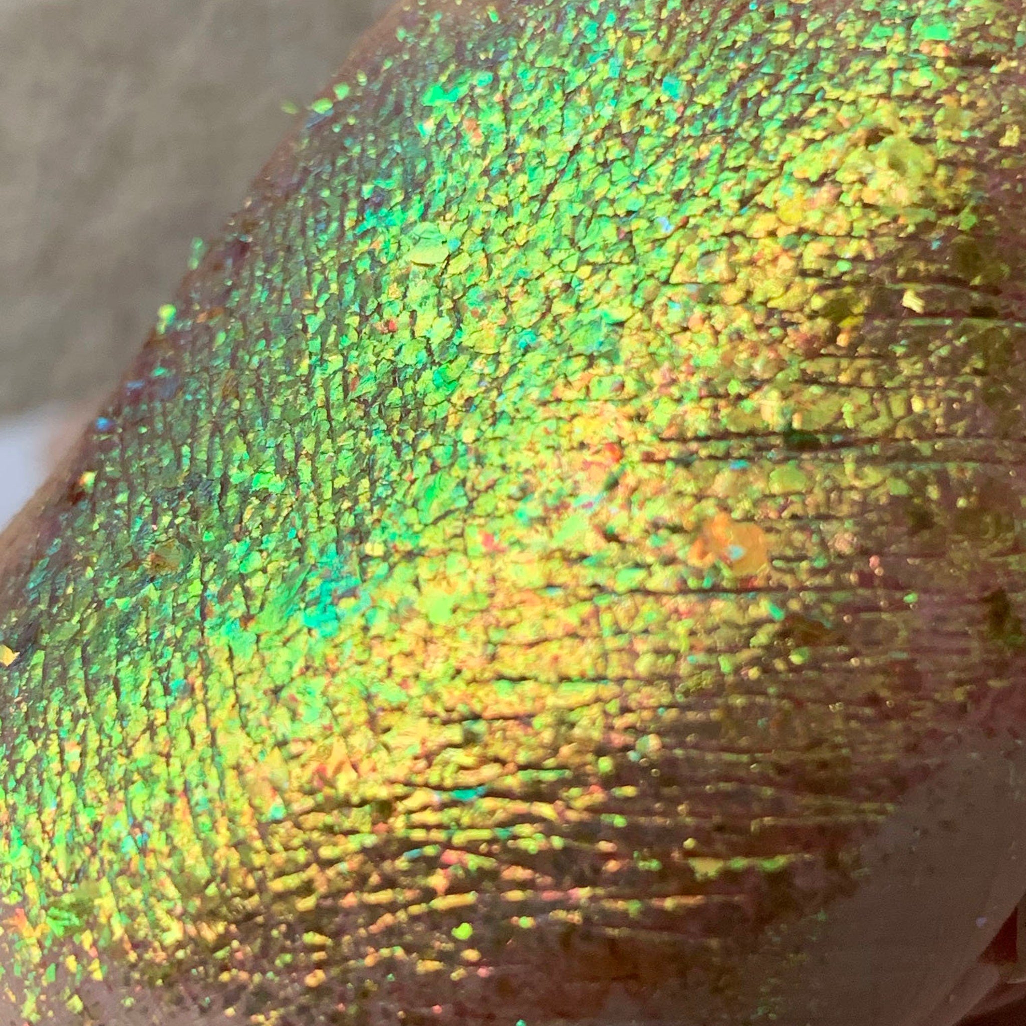 Iridescent green and yellow textured surface with cracked appearance on skin
