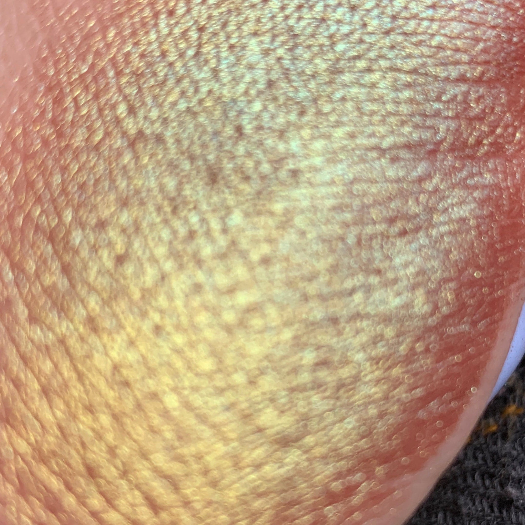 Gold and pink iridescent textured surface with circular bokeh effect on skin