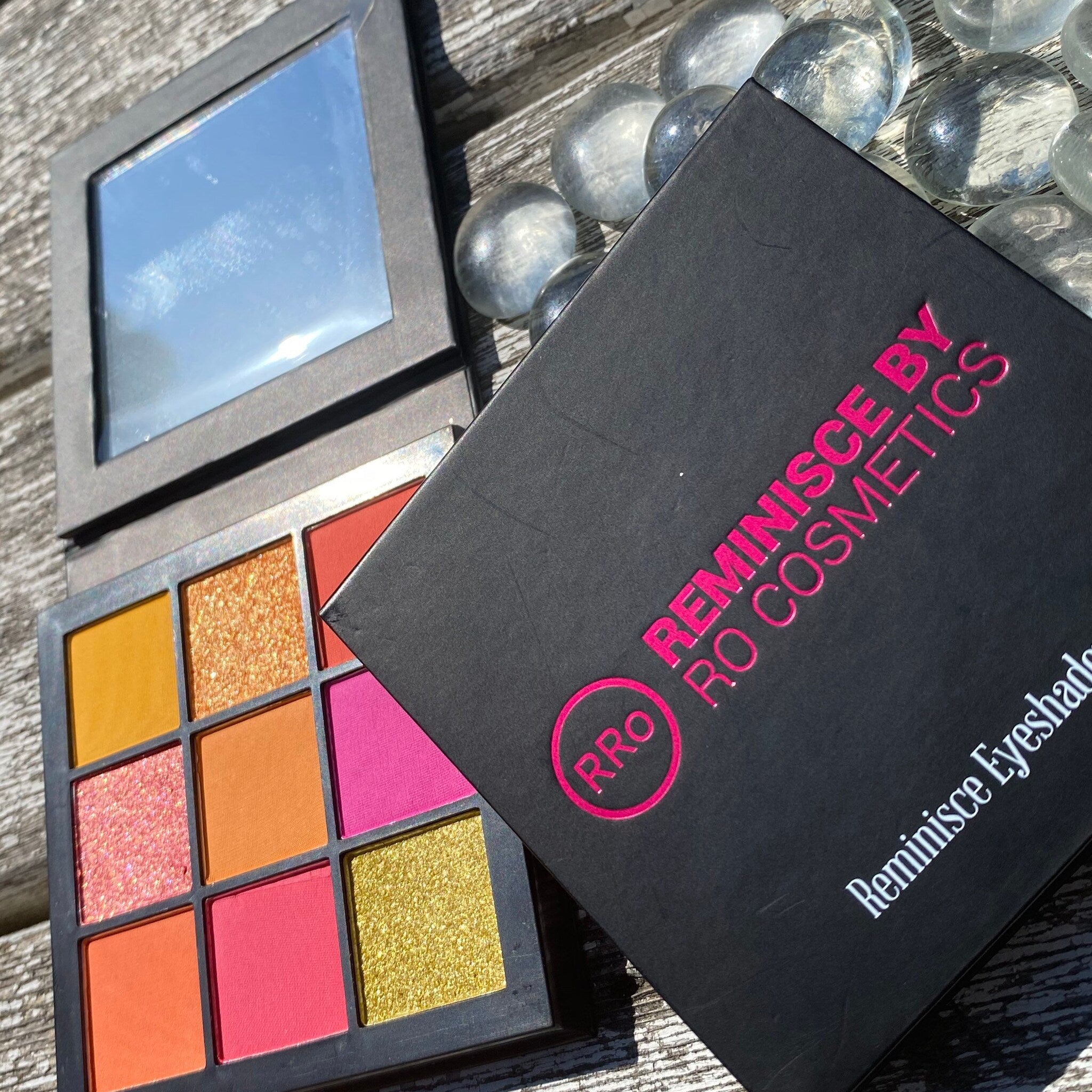 Eyeshadow palette with colorful shades, black compact, and Reminisce By RO Cosmetics logo