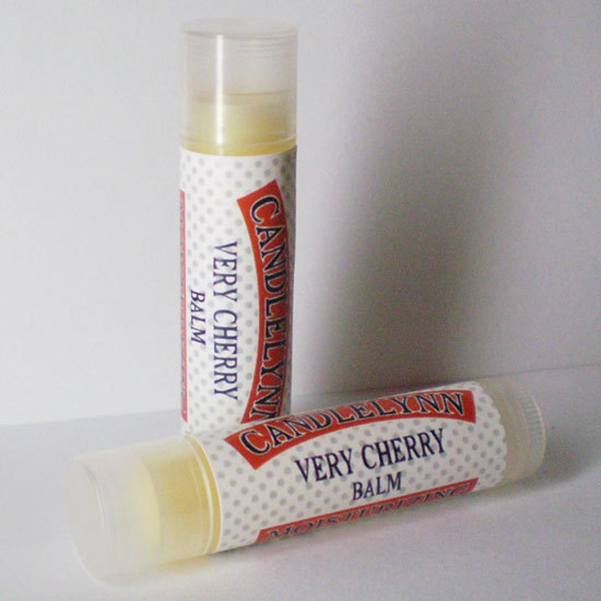 Lip balm tubes with white polka dot pattern, red text, and Candle Lynn brand name visible