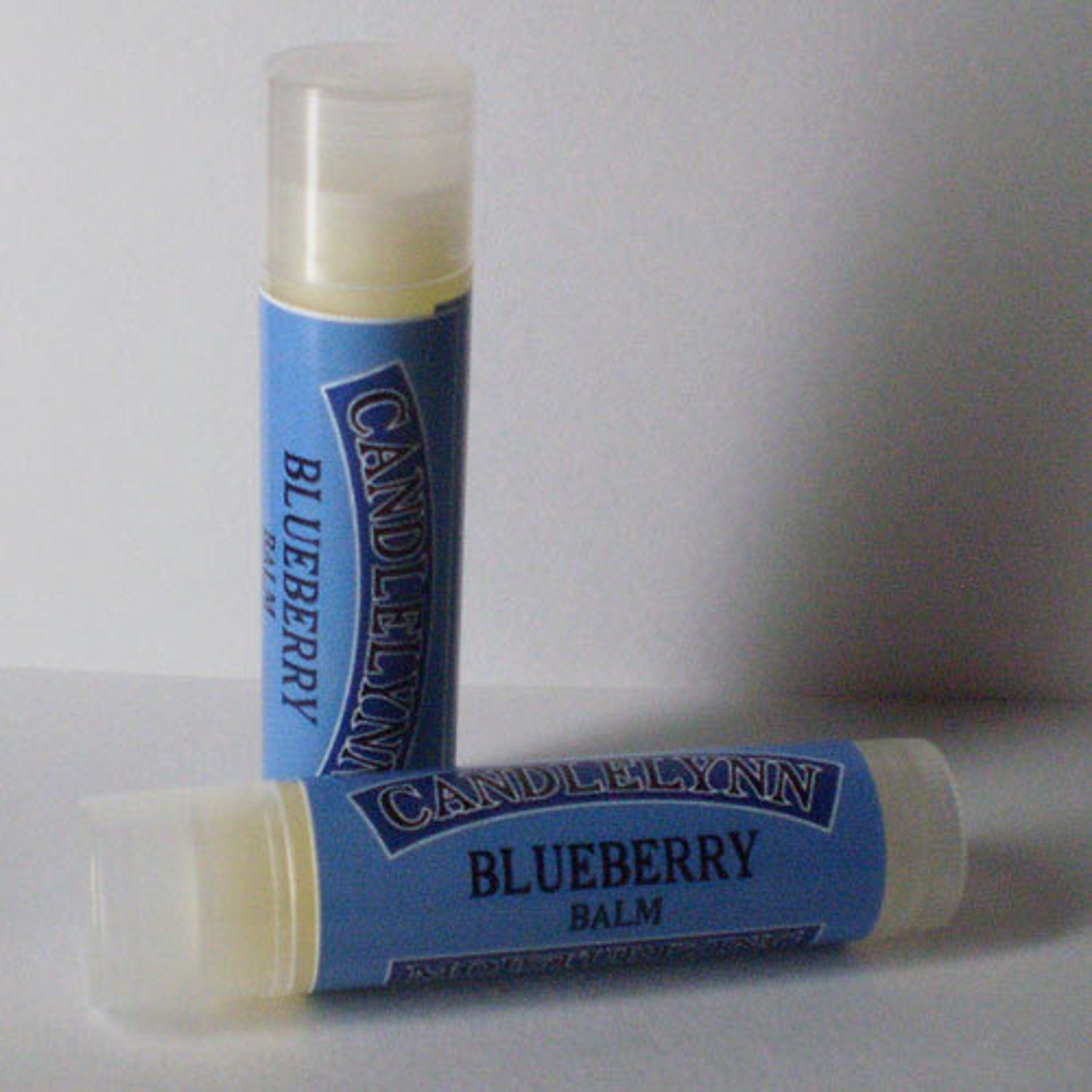 Lip balm tubes with blue labels and white caps, Candle Lynn Blueberry Balm visible