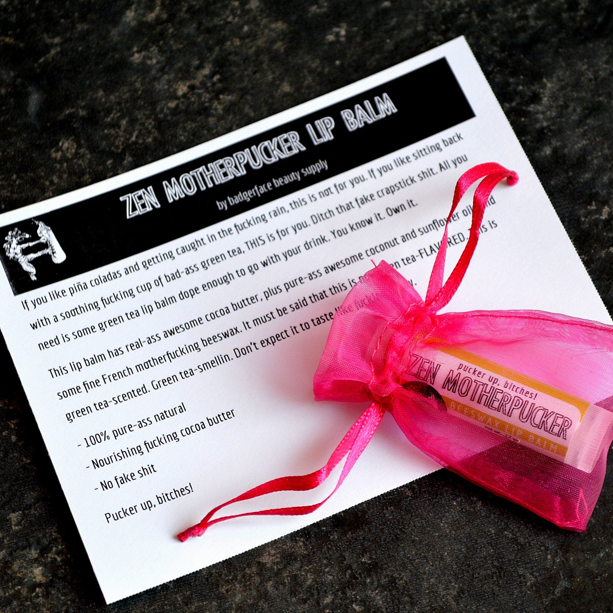 Lip balm in pink mesh bag with red ribbon, Zen Motherpucker lip balm label visible on white paper