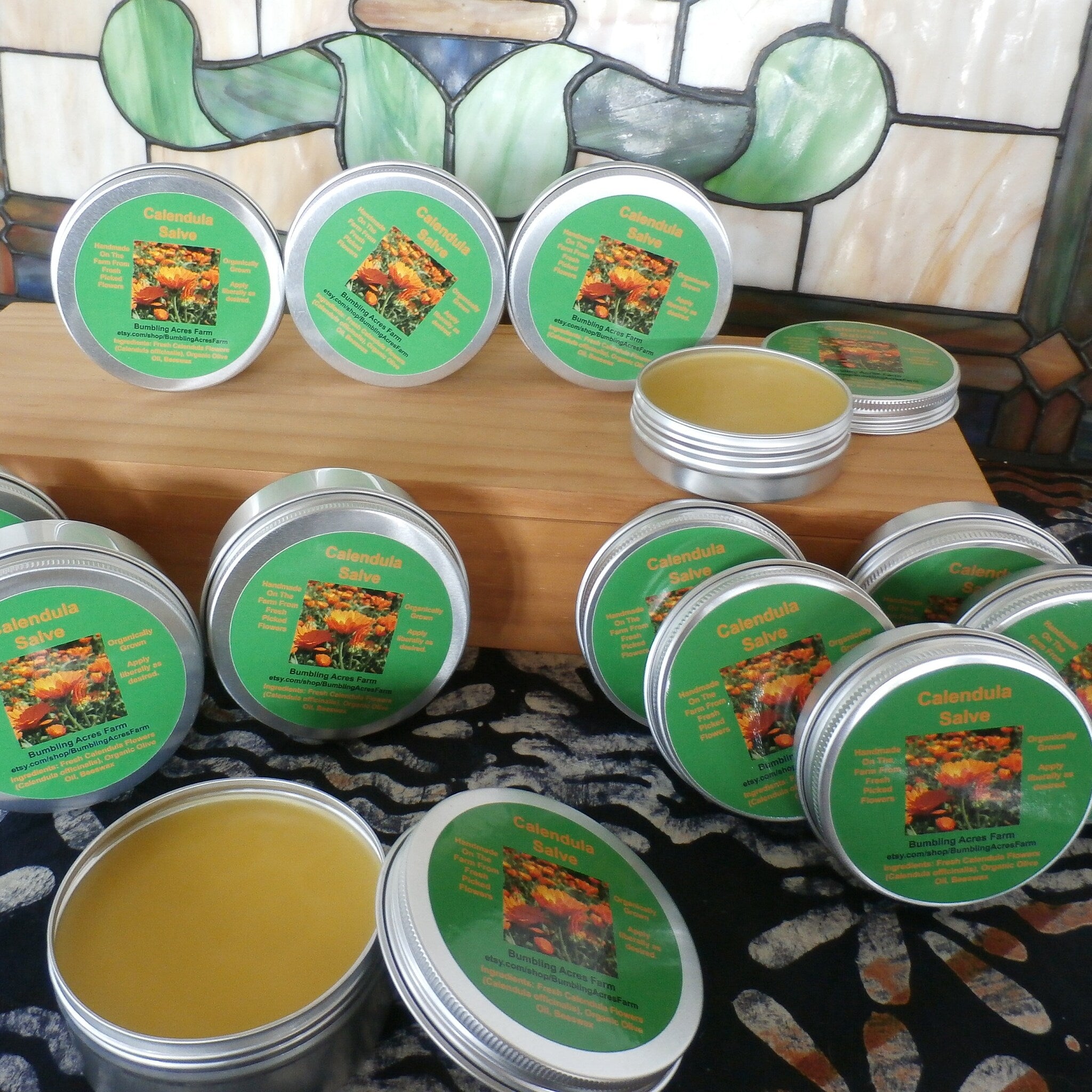 Calendula salve in silver tins with green labels, visible product and brand text on display