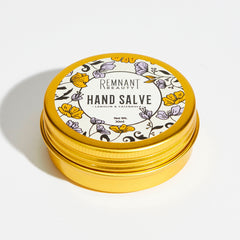 Hand salve in gold tin with floral pattern, Remnant Beauty branding visible