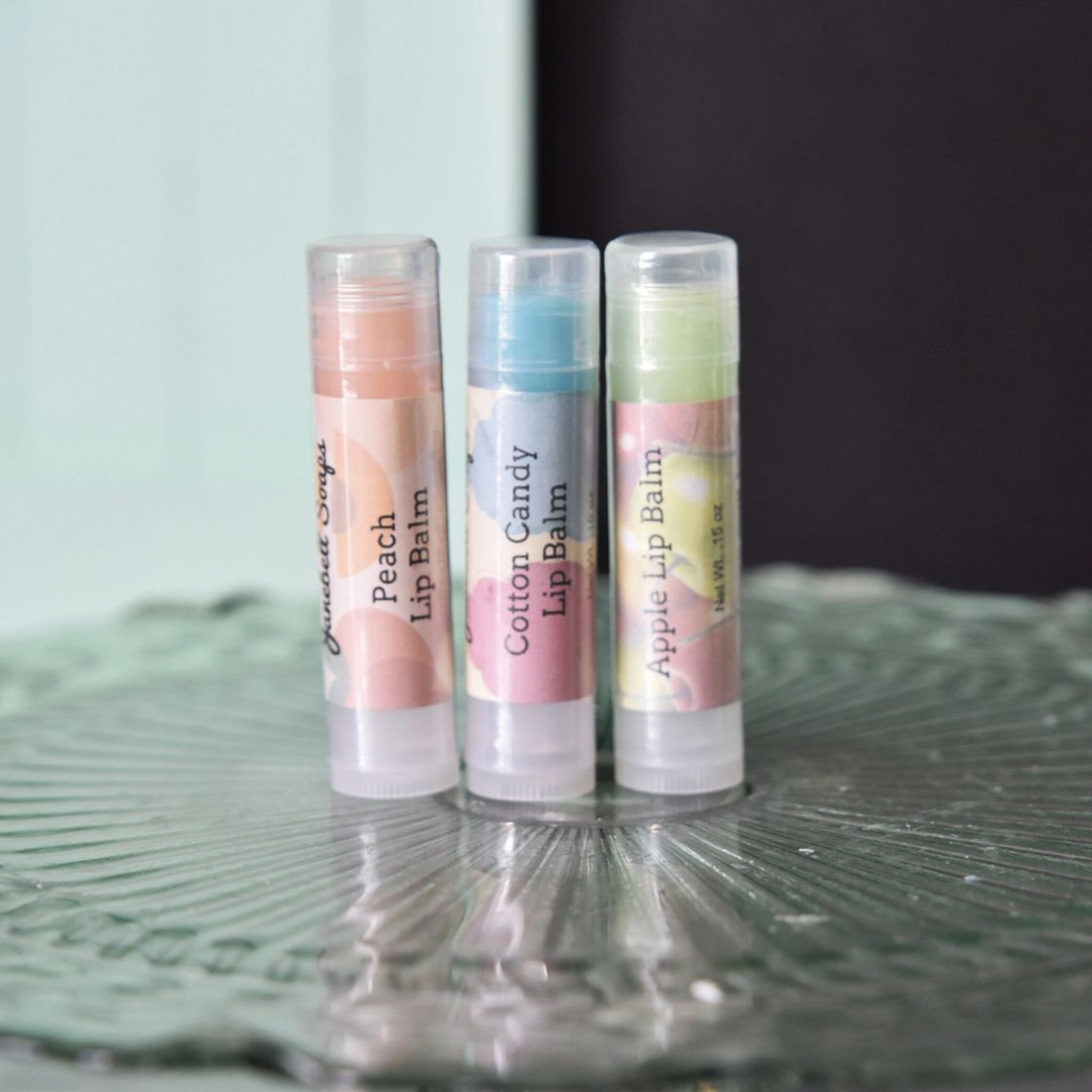Lip balm tubes in peach, blue, and green with clear caps, Janeoelt Soaps brand