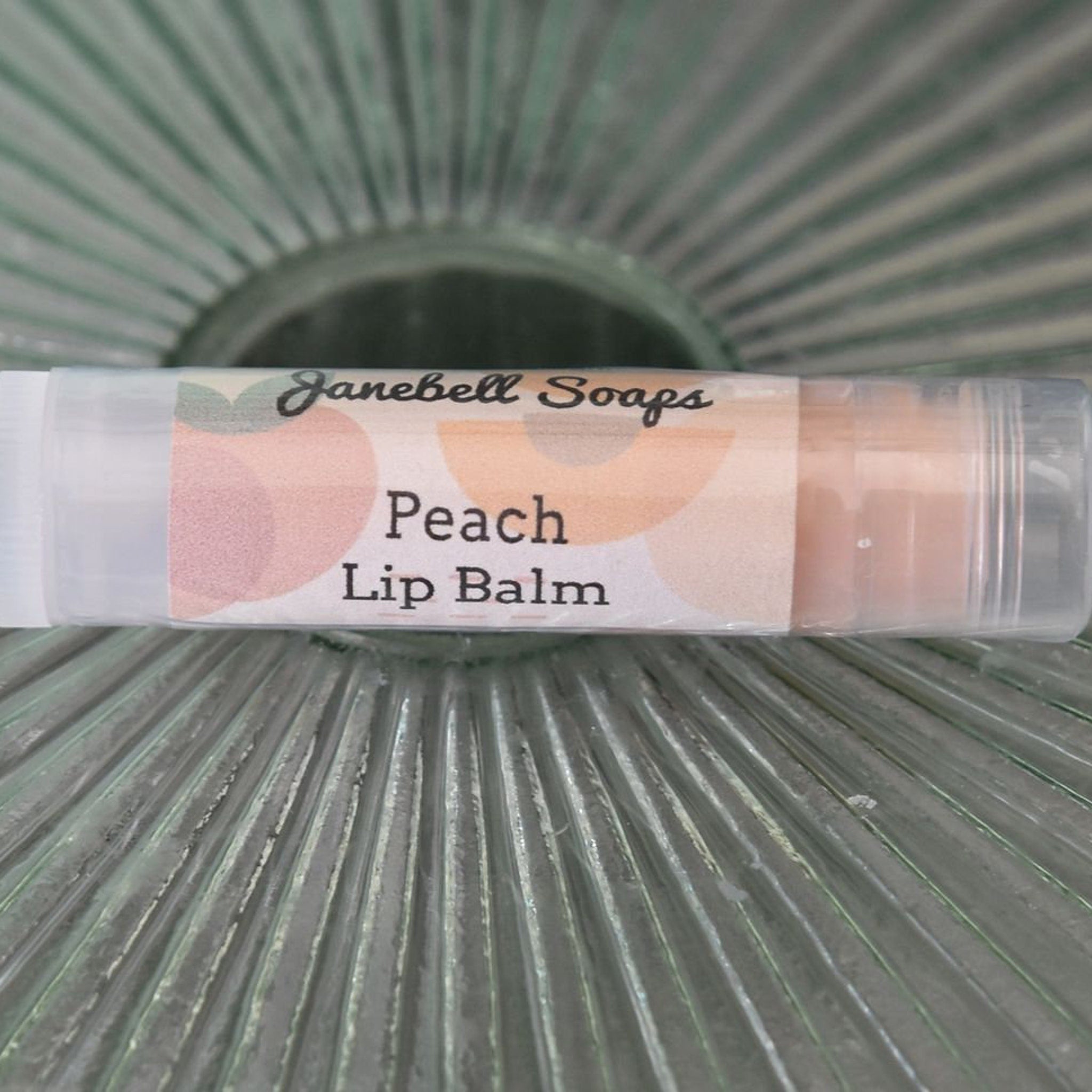 Peach lip balm in clear plastic tube with Janebell Soaps branding and peach graphic