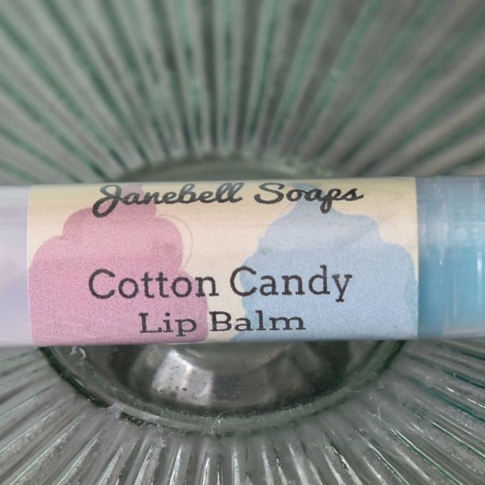 Lip balm tube with pink and blue label, "Janebell Soaps" text, and cotton candy flavor