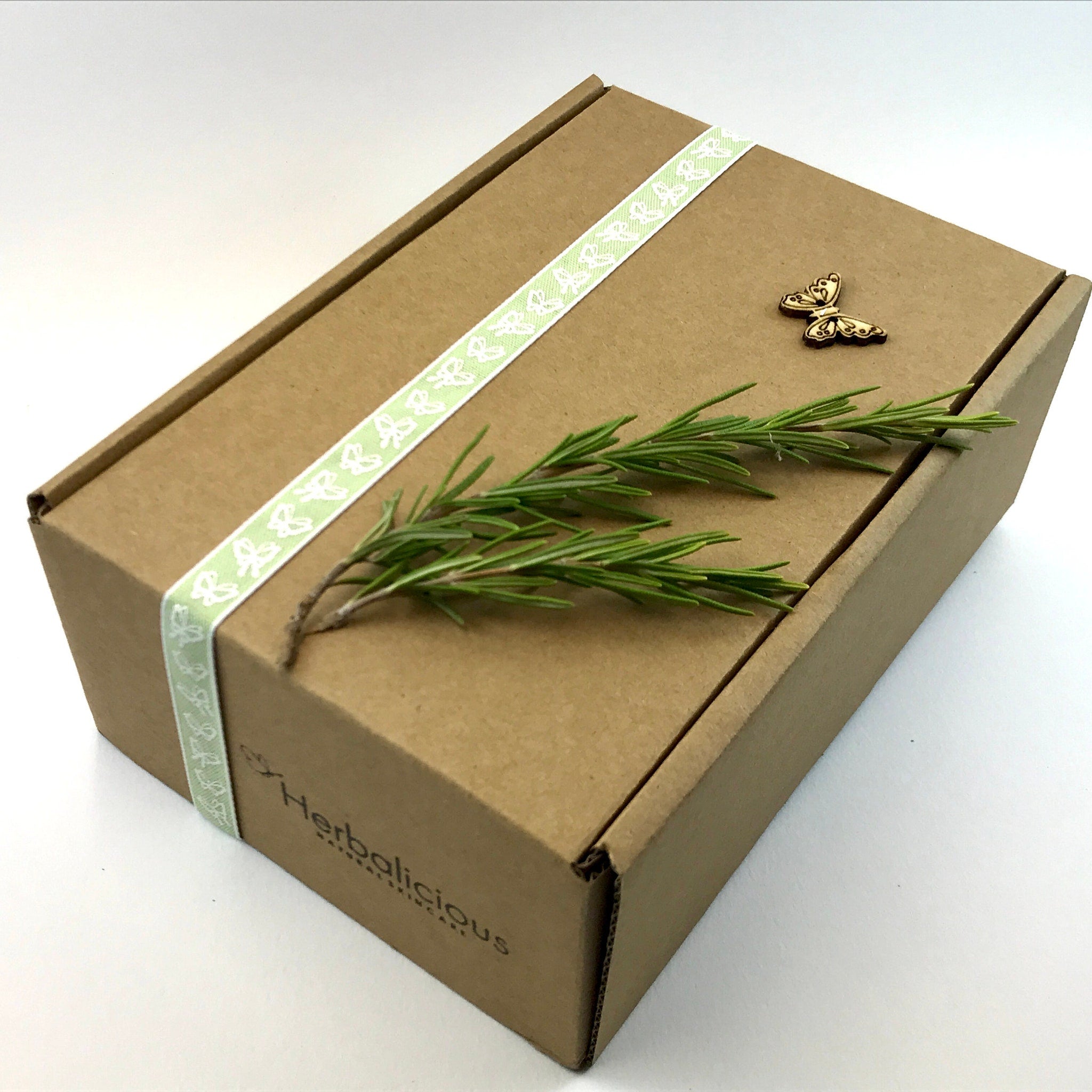 Gift box with brown cardboard, green butterfly ribbon, and wooden butterfly decoration